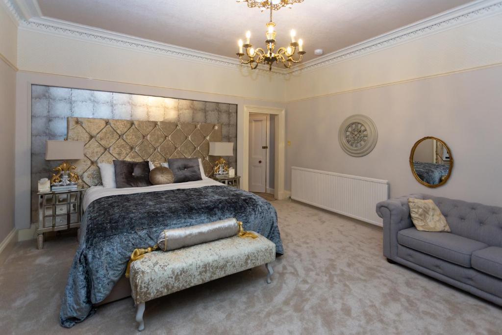 a bedroom with a bed and a couch and a chandelier at Trinity Boutique B&B in Peterhead