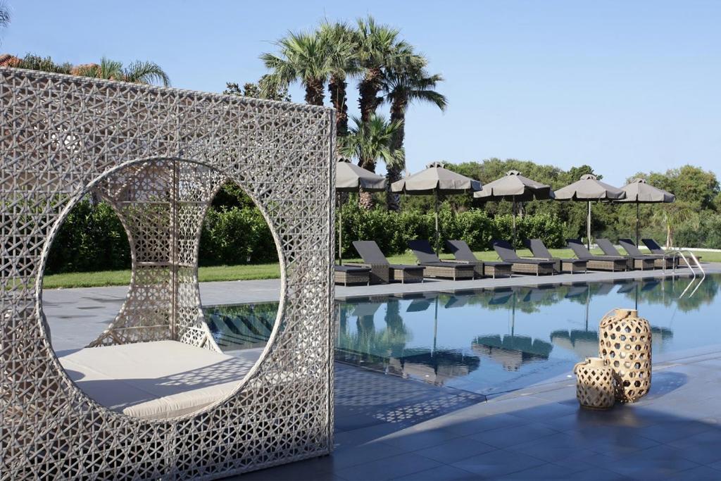 una piscina in un resort con sedie a sdraio e specchio di Lagouvardos Village Hotel a Marathópolis