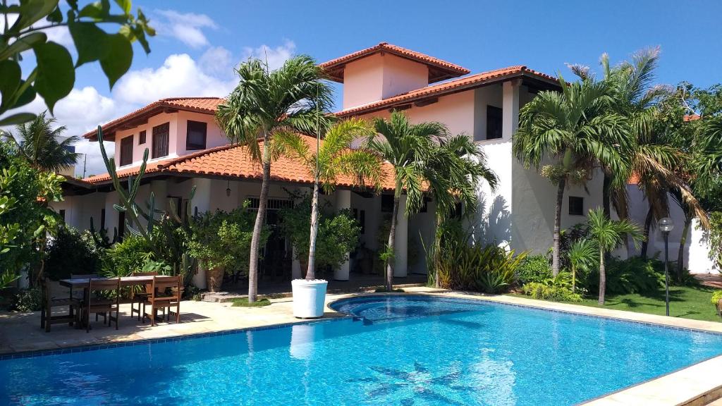 a villa with a swimming pool in front of a house at Hospedaria Chez Nous in Caucaia