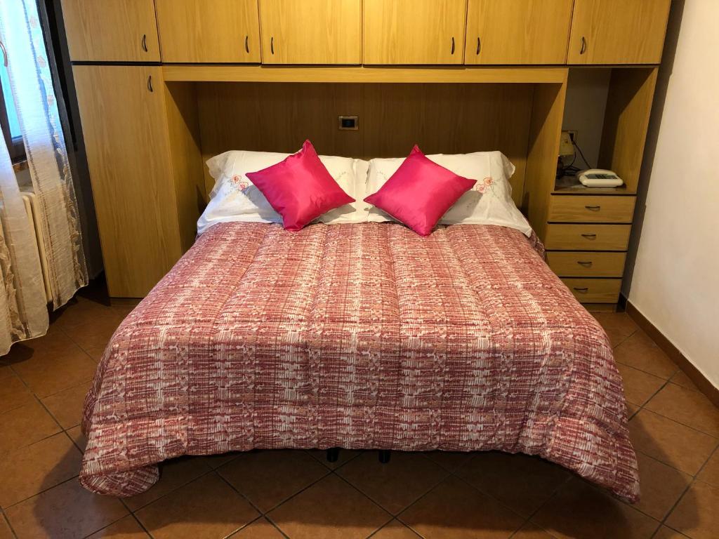 1 cama grande con 2 almohadas rojas. en La Suite & Al Giardino, en Ferrara