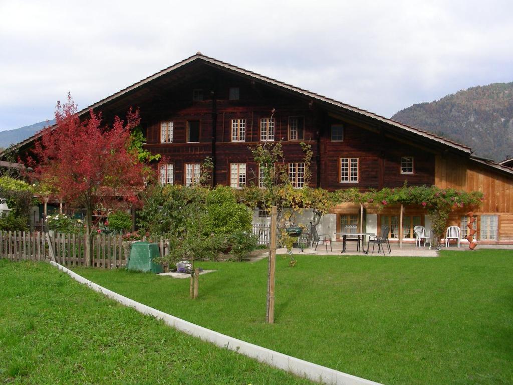 ein großes Holzhaus mit grünem Rasen davor in der Unterkunft Holidayapartment Sydach in Wilderswil