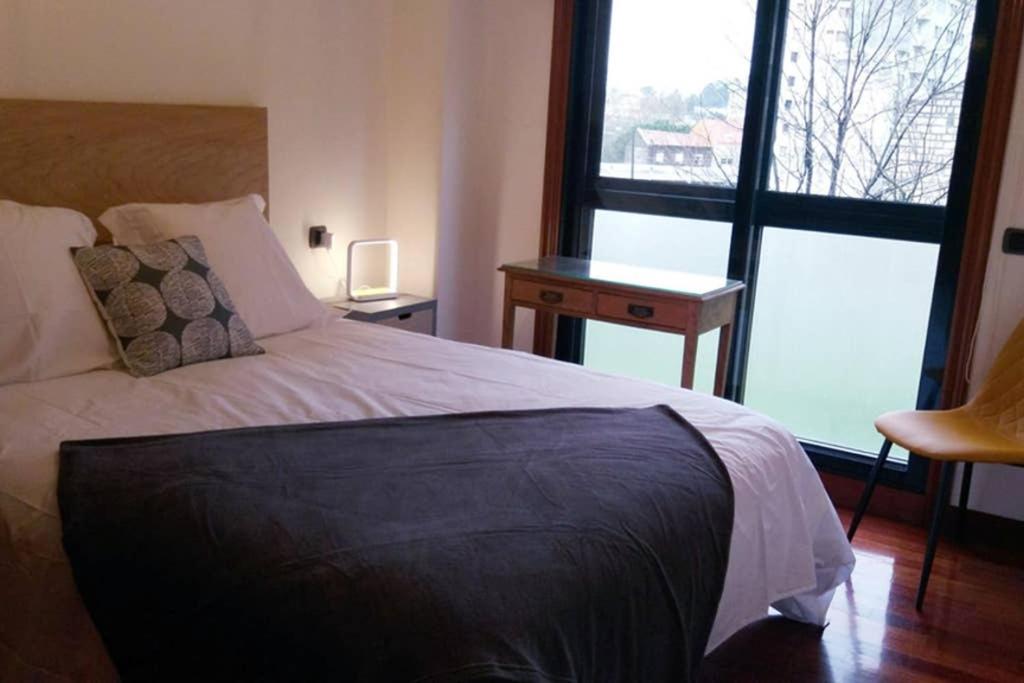 una camera con letto, scrivania e finestra di Apartamento completo con parking privado y WiFi en San Roque a Vigo