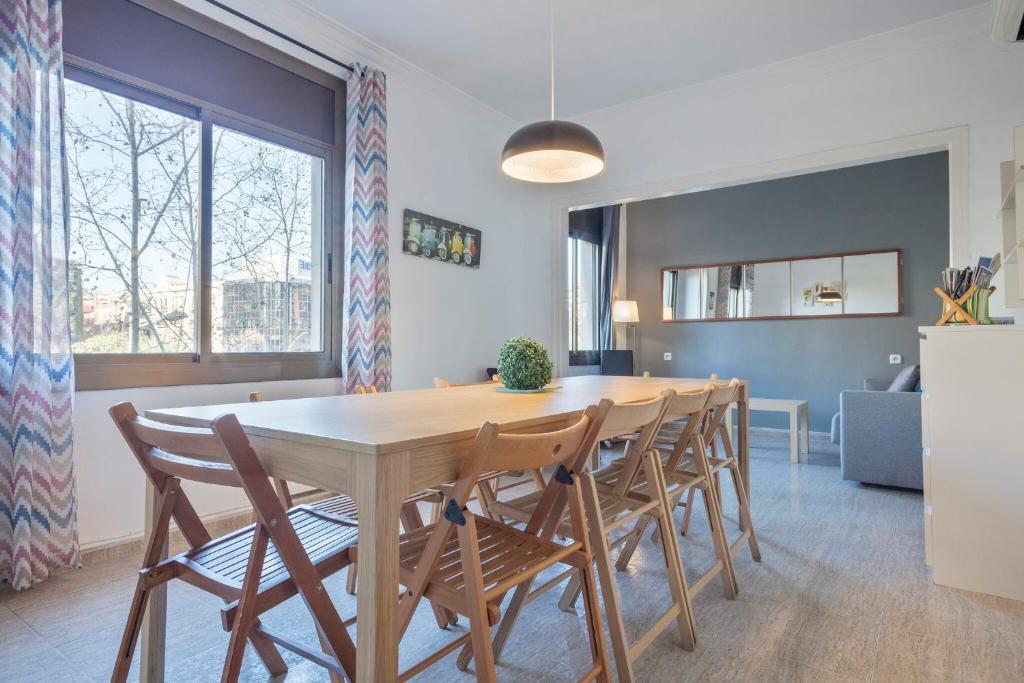 cocina y comedor con mesa de madera y sillas en Apartamentos Tarradellas Sants Estació, en Barcelona