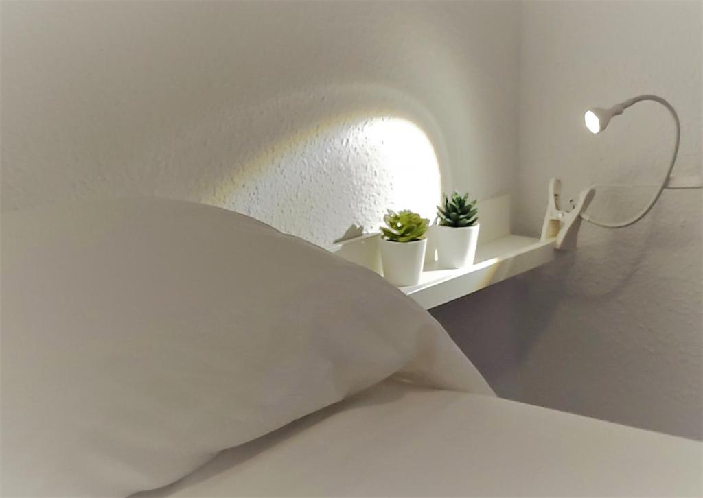 a white bed with a pillow and plants on a shelf at El Mirador de Cadiz in Cádiz