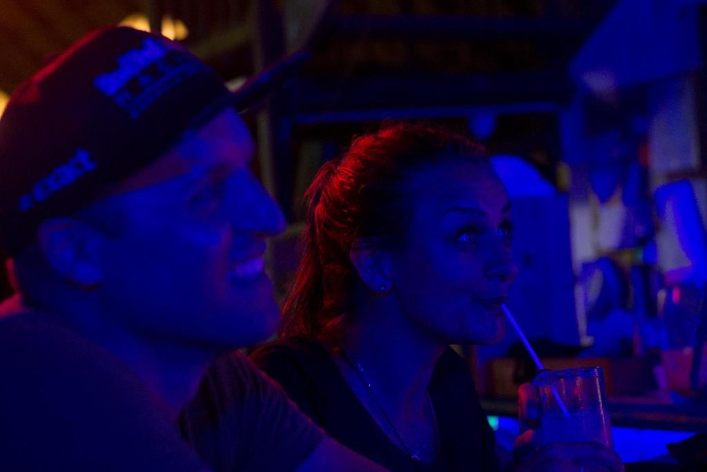 a man and woman sitting in a bar smoking at El Zoo Hostel, Bar & Pool in Palomino