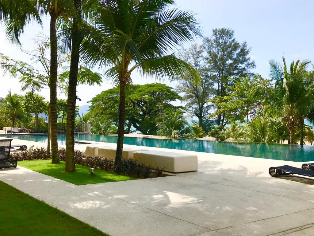 a swimming pool with palm trees in front of it at By The Beach - Luxury 2 Bedrooms Family Suite in Batu Ferringhi
