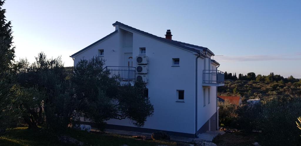 una casa blanca en la cima de una colina en Apartments Zafranović, en Prvić Luka