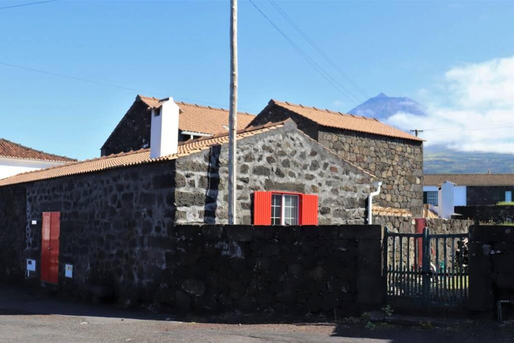 een stenen huis met rode deuren en een hek bij Adega do Xelica - Holiday Cottage in Arcos