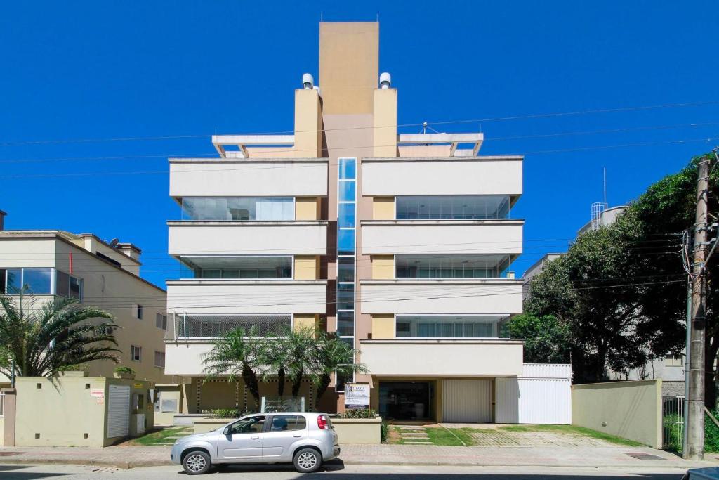 un coche aparcado frente a un edificio alto en Aluguel Apartamento 2 quartos s/1 suíte | Bombas/SC, en Bombinhas