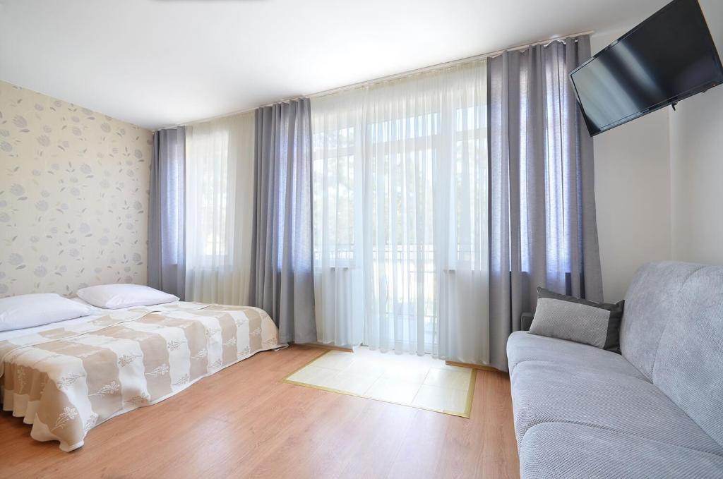 a bedroom with a bed and a couch and a tv at Pokoje Sztormowa 15 in Pogorzelica