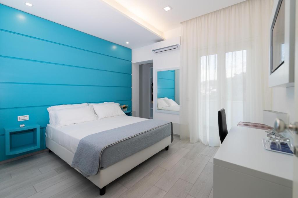 a bedroom with a blue accent wall and a bed at Dreams Tropea Mare in Tropea