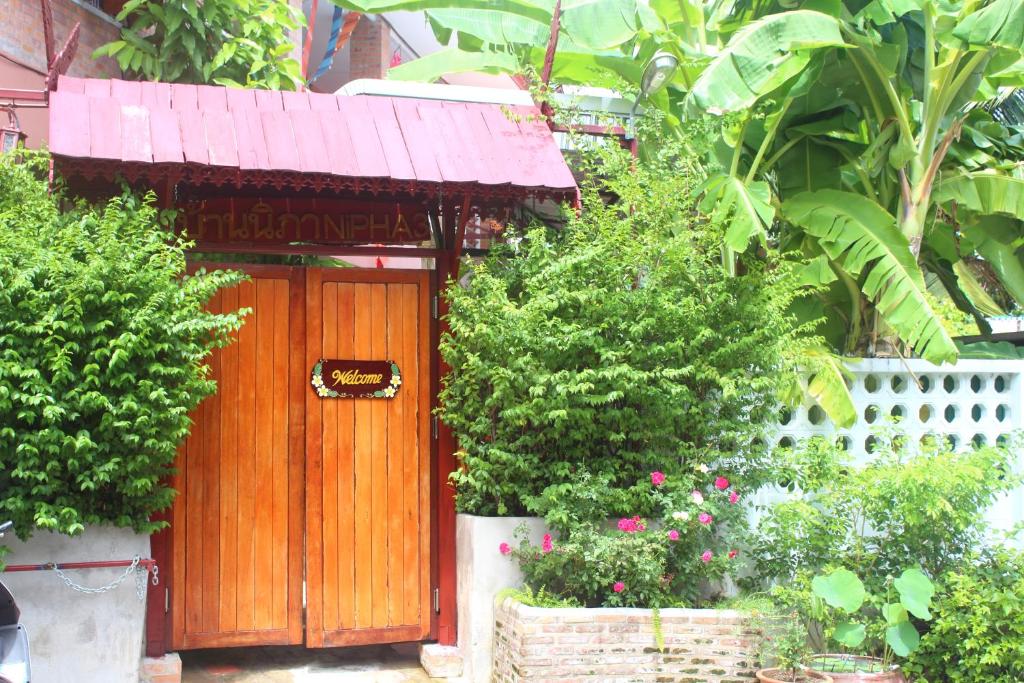 a wooden door in a garden with some plants at Boutique House Nipha in Chiang Mai