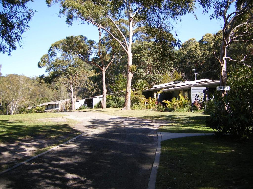 a house in the middle of a yard with trees at Sandpiper On Smiths Lake in Smiths Lake