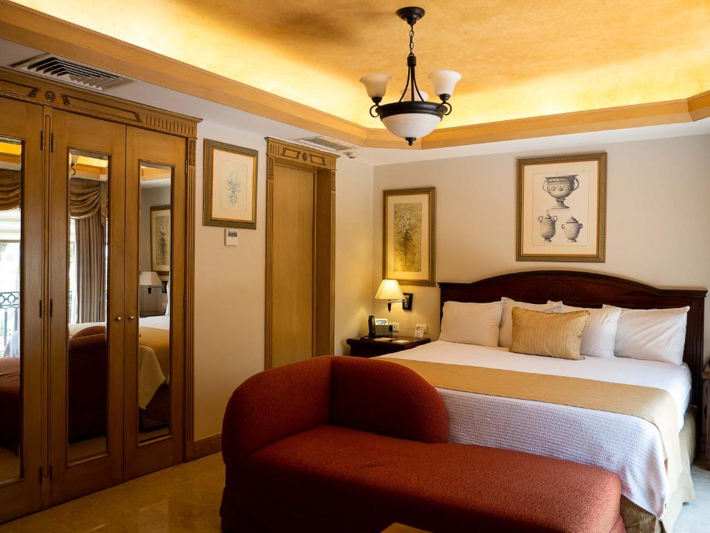 Hotel Hacienda Real في سيوداد ديل كارمن: غرفة نوم بسرير وكرسي