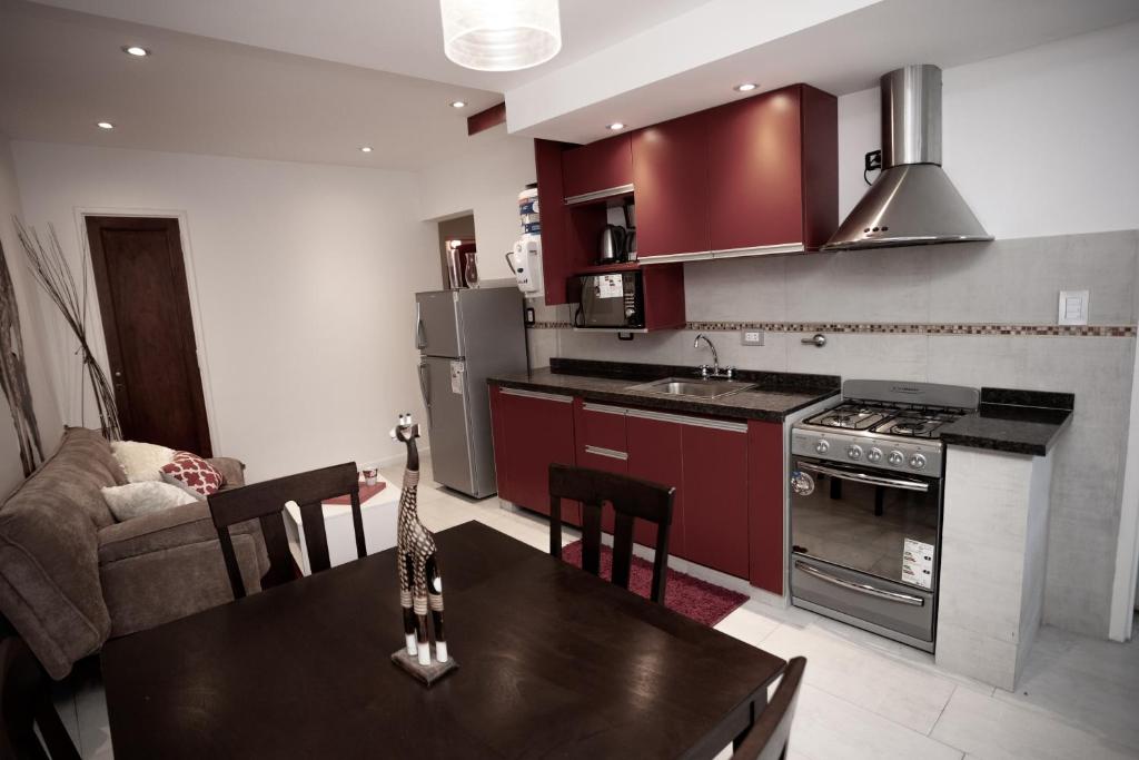 una cocina con armarios rojos y una mesa con sillas. en 9 ¾ Apartamentos VIP en La Falda