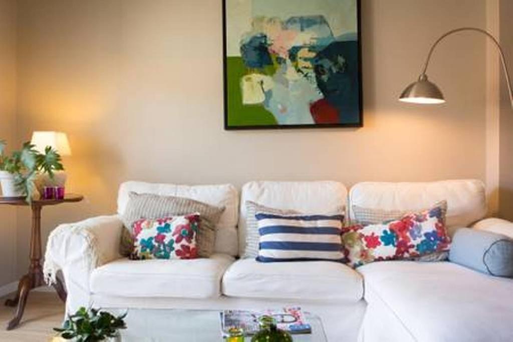 een woonkamer met een witte bank met kussens bij Peaceful Top Floor Apt W Balconies - Cambridge RIGHT - AC in Funchal