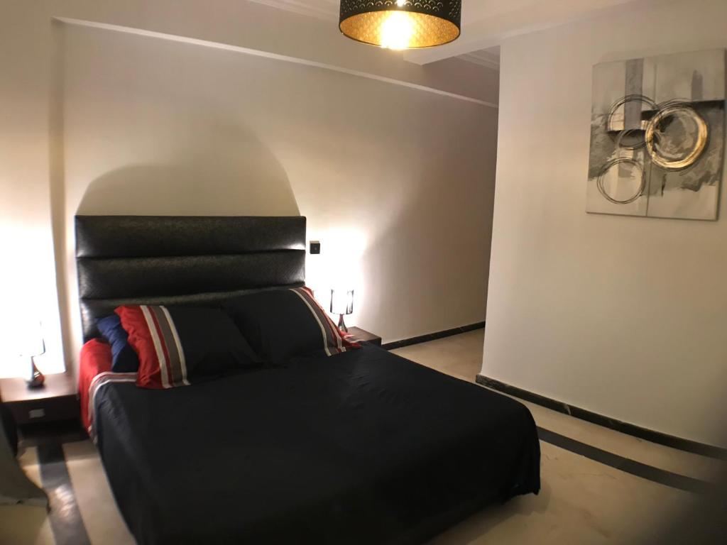 1 dormitorio con 1 cama negra en una habitación en Annakil Appart, en Marrakech