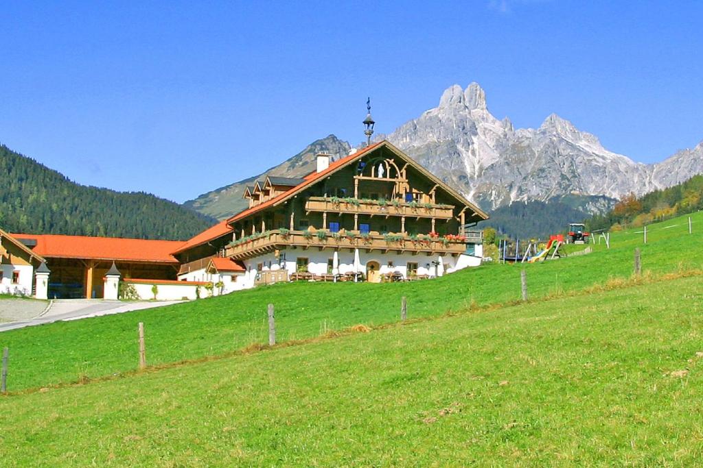 a large building on a hill with mountains in the background at Appartement Pilzhof in Filzmoos