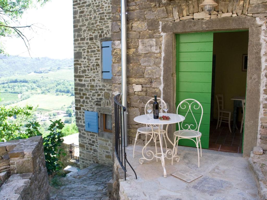 un patio con mesa y sillas frente a una puerta verde en Casetta Melon, en Motovun