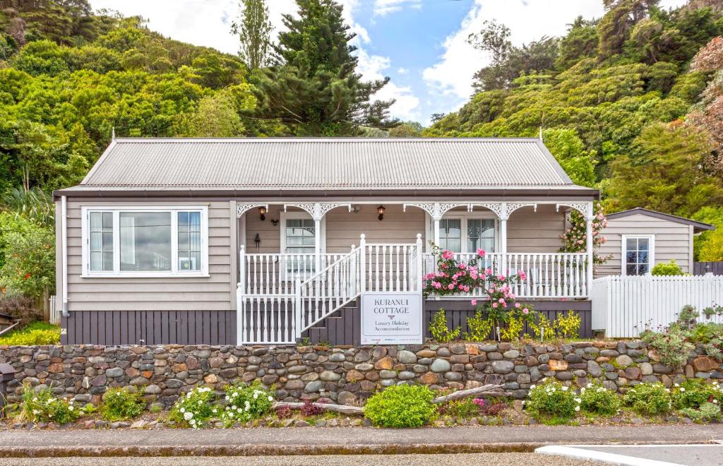a small house with a stone wall in front of it at Kuranui Cottage in Thames