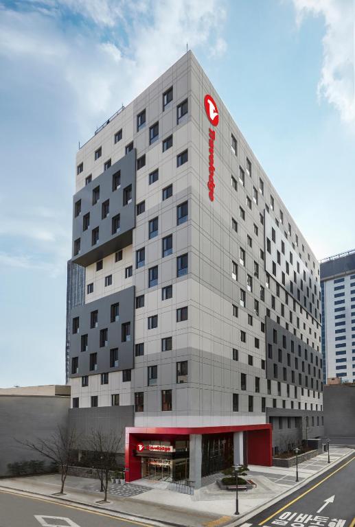 a tall white building with a red sign on it at Travelodge Myeongdong Euljiro in Seoul