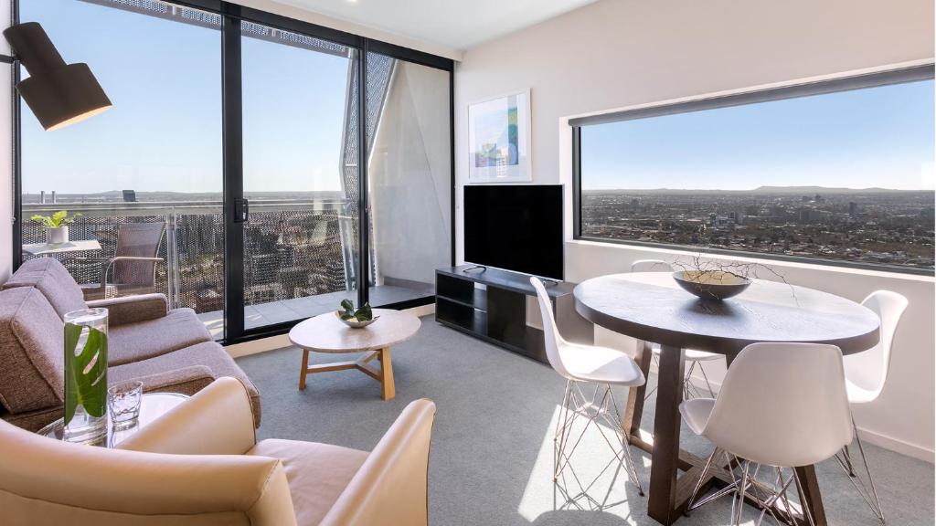 a living room filled with furniture and a large window at Oaks Melbourne on William Suites in Melbourne