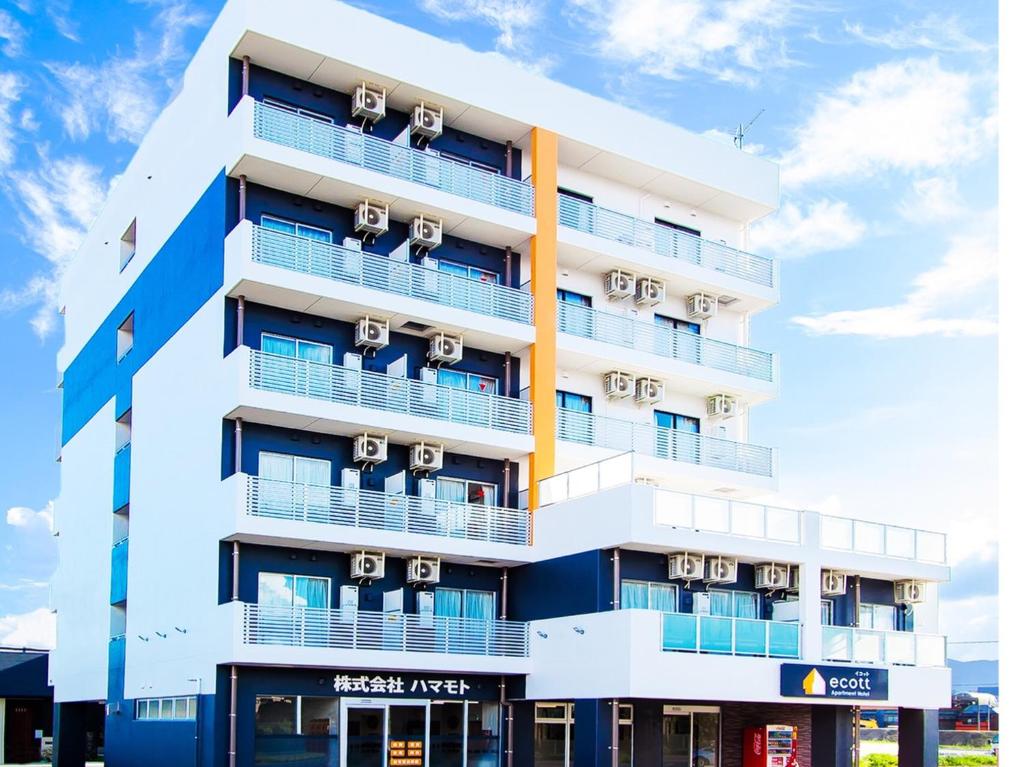 an apartment building with white and blue balconies at Apartment Hotel Ecott in Kagoshima