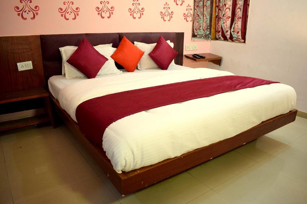 een slaapkamer met een groot bed met rode en witte kussens bij Radhe-The Hotel in Vadodara