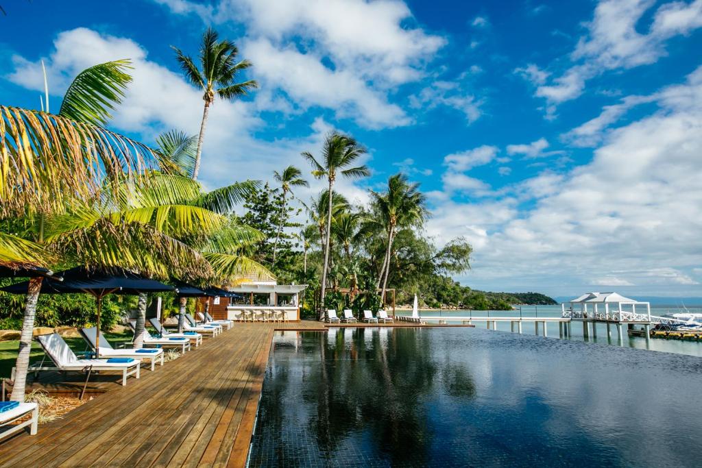 a pool at a resort with lounge chairs and the ocean at Orpheus Island Lodge in Orpheus Island