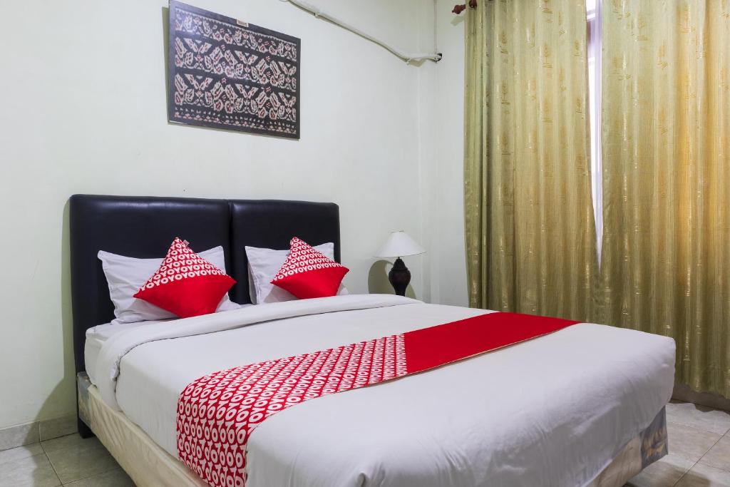 1 dormitorio con 1 cama grande con almohadas rojas en Super OYO 1682 Greenia Hotel, en Kupang