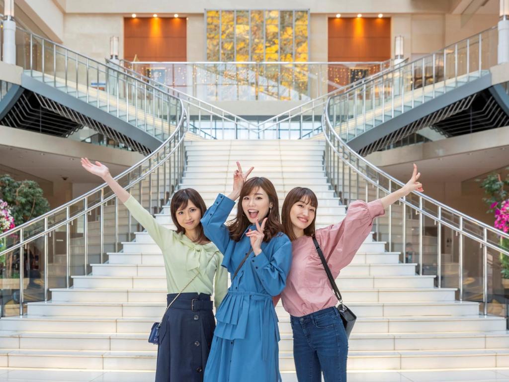 two girls posing for a picture in front of a stairway at Hotel Keihan Universal Tower in Osaka