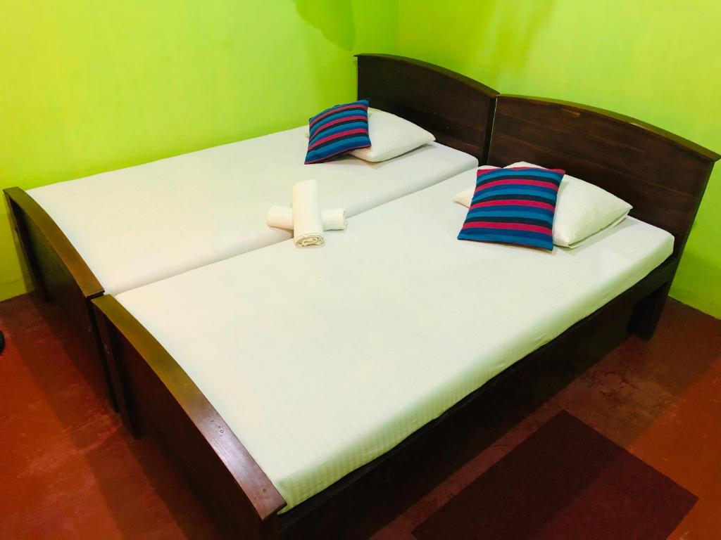 two twin beds in a room with green walls at Kumari Guest House in Polonnaruwa