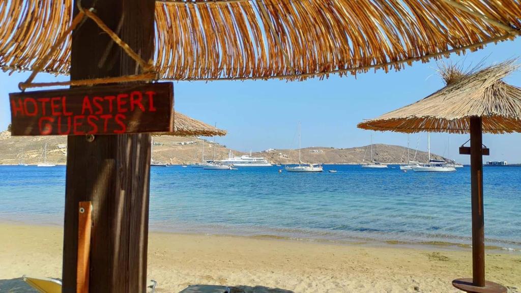 a hotel agent sign on a beach with a thatch umbrella at Asteri Hotel in Livadi
