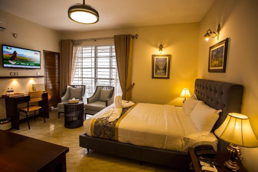 a bedroom with a bed and a desk and a tv at Shinepukur Suites in Dhaka