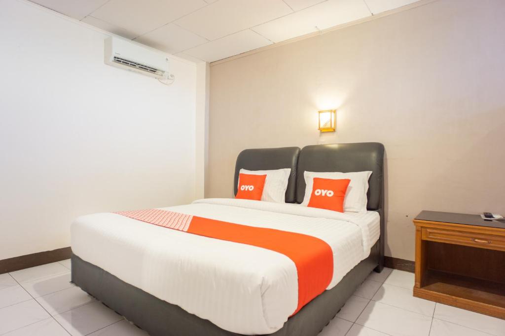 a bedroom with a large bed with orange and white pillows at OYO 2180 Vina Vira Hotel in Lhokseumawe