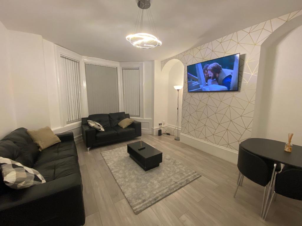 ein Wohnzimmer mit einem Sofa und einem TV an der Wand in der Unterkunft Heaton Park Road Professional Lets in Newcastle upon Tyne