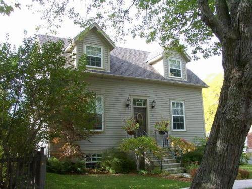 Una casa blanca con un árbol delante. en Antique Slumber Old Town Bed & Breakfast, en Niagara on the Lake