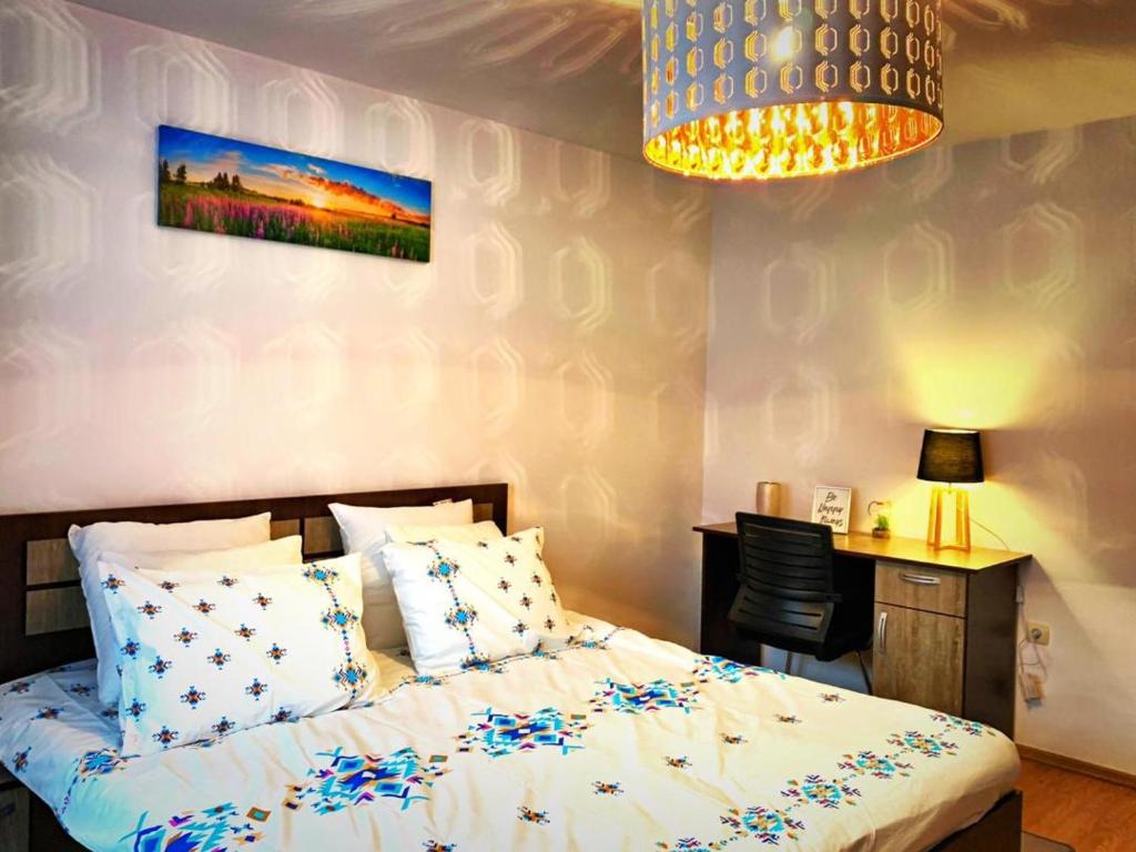 a bedroom with a bed and a desk and a lamp at Cozy Studio in Cugir