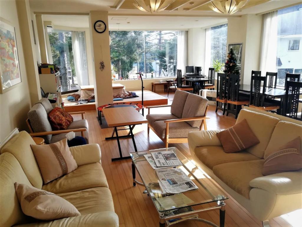 a living room with couches and chairs and a table at K's House Hakuba Alps - Travelers Hostel in Hakuba
