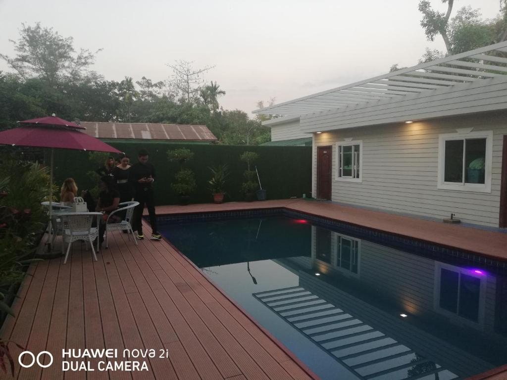 un gruppo di persone in piedi accanto a una casa con piscina di Supreme Hotel Yangon a Yangon