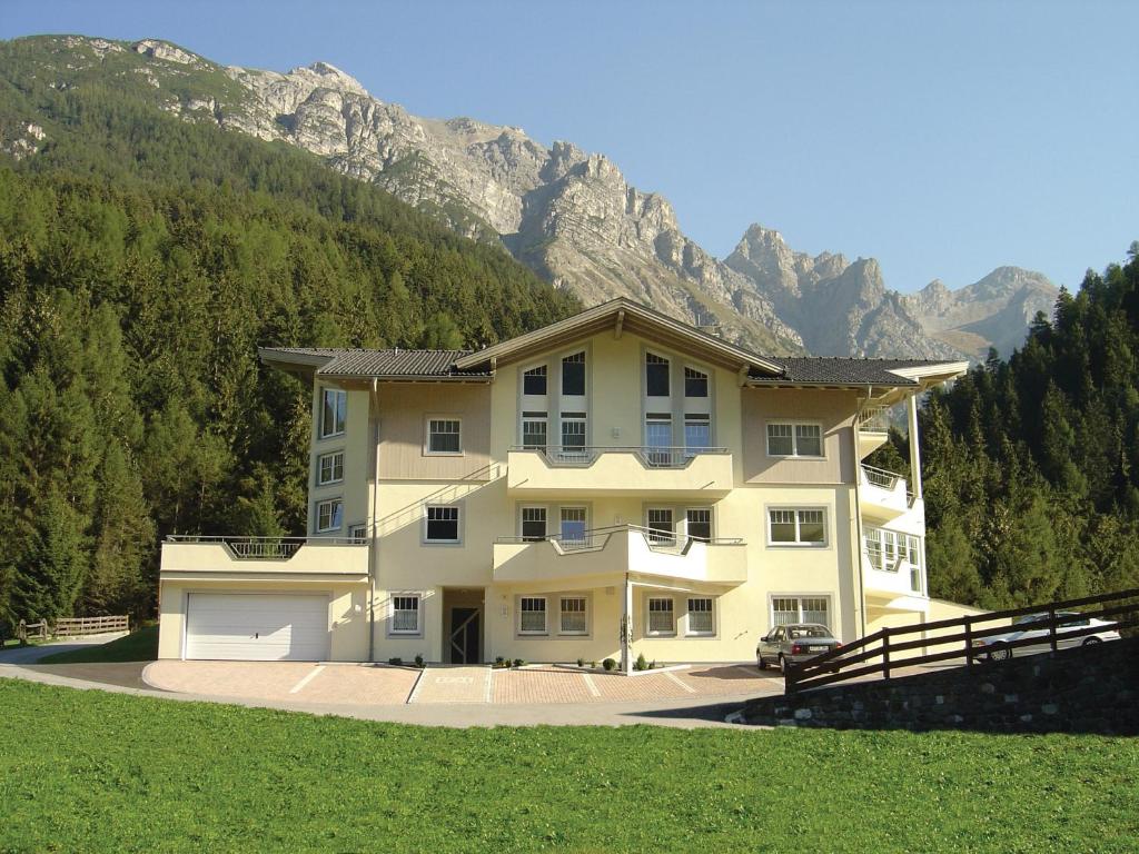 une grande maison en face d'une montagne dans l'établissement Appartementhaus Pinnisblick, à Neustift im Stubaital