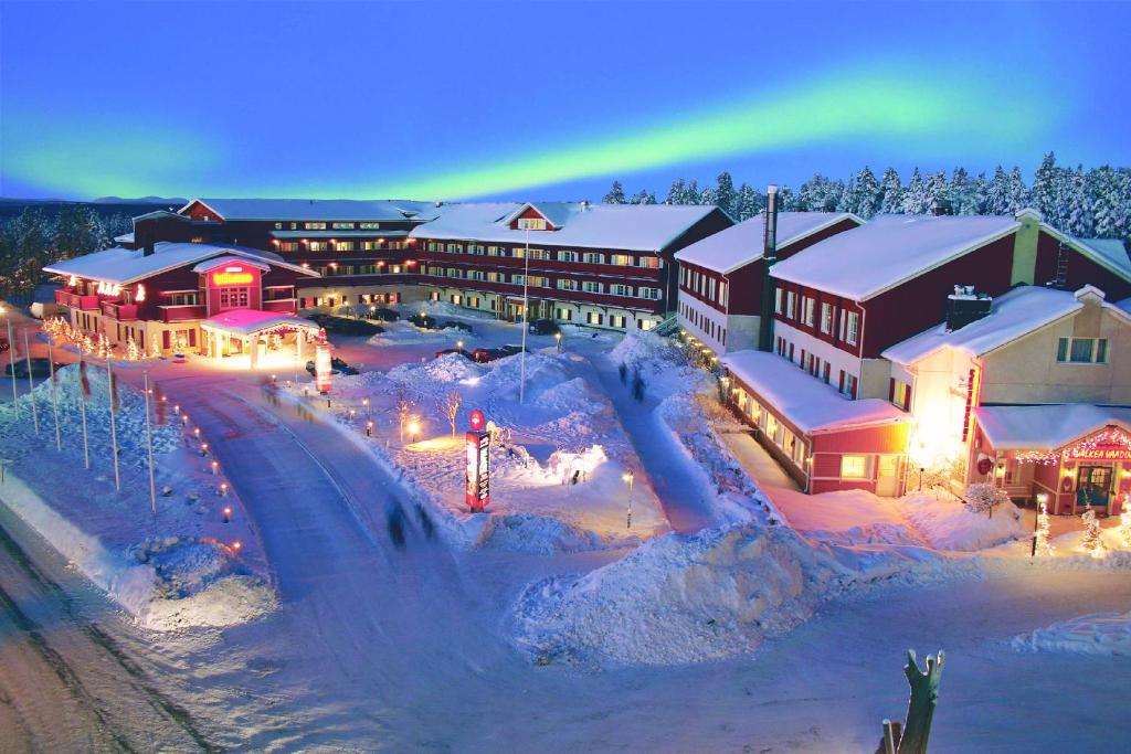 a lodge with a rainbow in the sky over a snow covered town at Hotel Hullu Poro in Levi