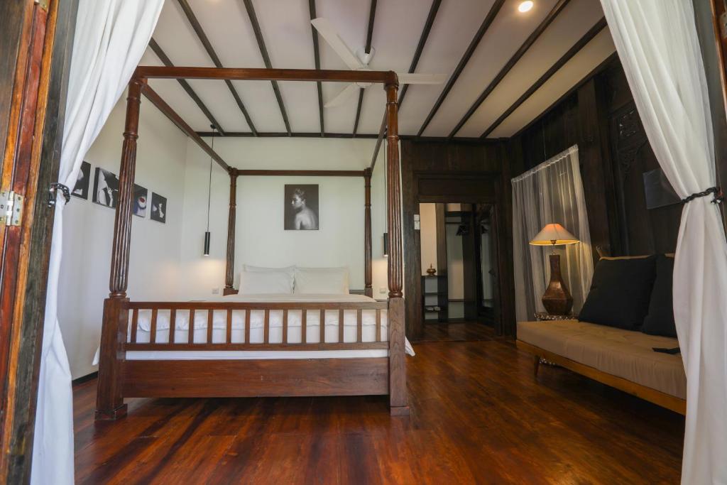 1 dormitorio con cama con dosel y sofá en Cabin 2, en Batu