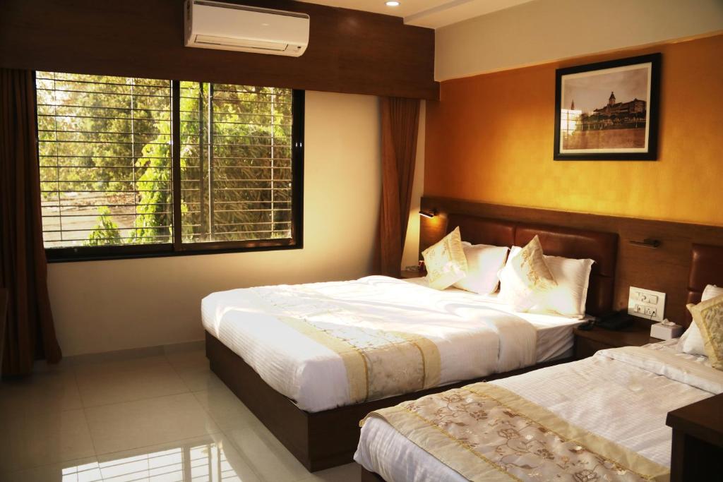 a hotel room with two beds and a window at Hotel Crystal Luxury Inn- Bandra in Mumbai