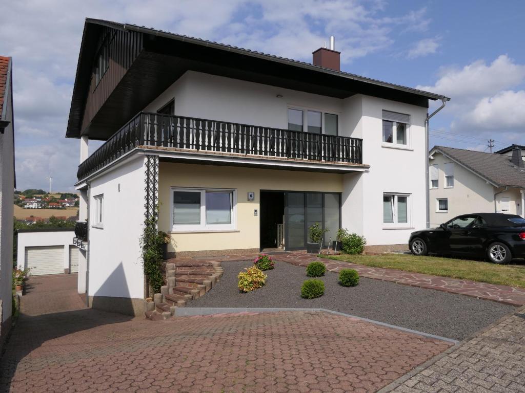 uma casa branca com uma varanda e uma entrada em Ferienwohnung Jürgen Brill em Eppelborn