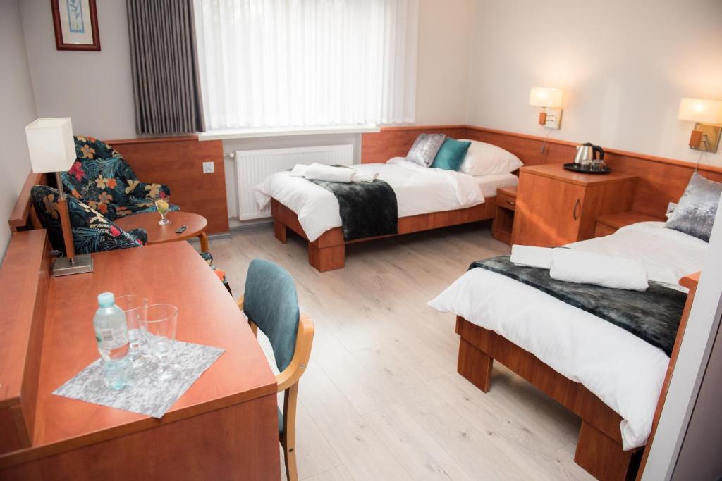 een hotelkamer met 2 bedden en een tafel en stoelen bij Geris in Częstochowa
