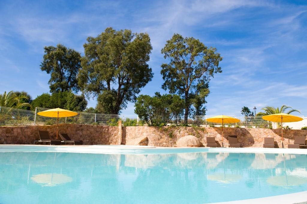 a swimming pool with yellow umbrellas and chairs at Alzitone in Ghisonaccia