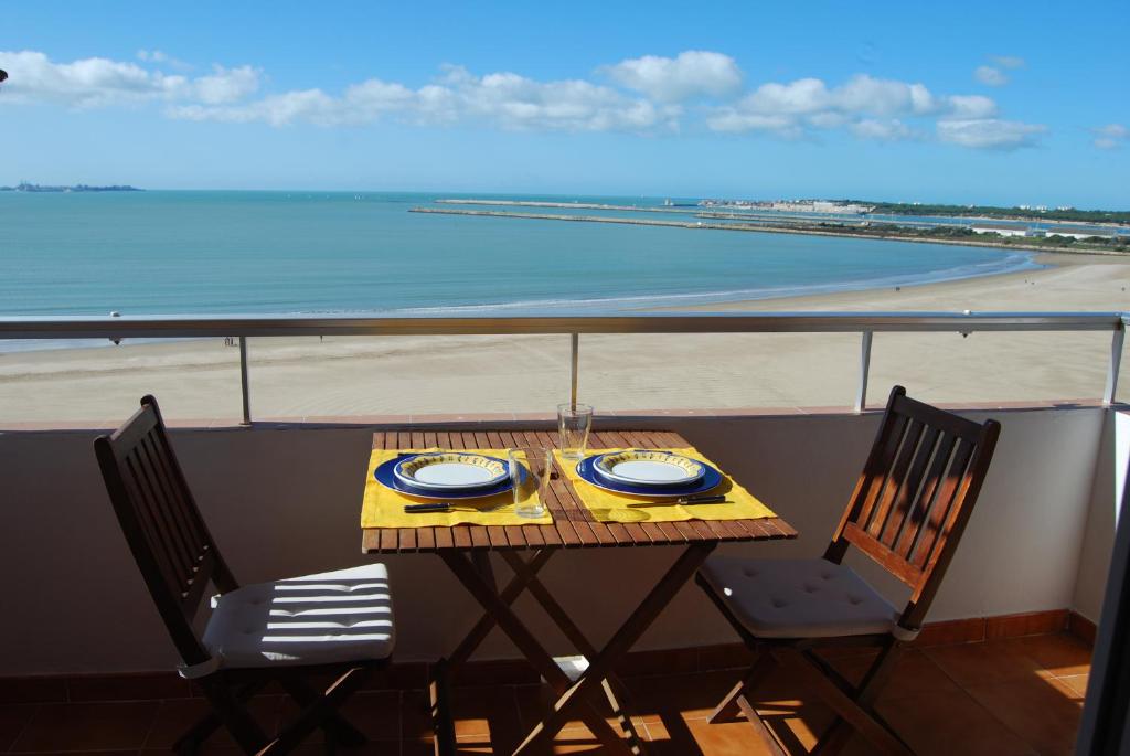 een tafel en stoelen op een balkon met uitzicht op het strand bij La casa De Los Faros in El Puerto de Santa María