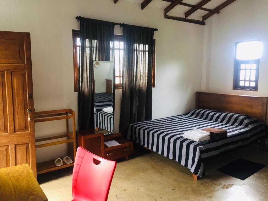 1 dormitorio con cama, espejo y silla en Upland Inn en Kandy