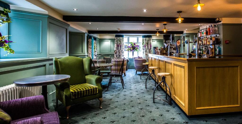 a bar in a pub with green chairs and tables at The Wyndham Hotel in Clearwell